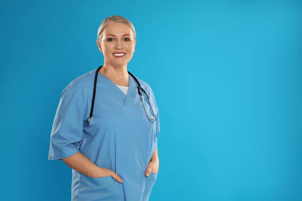 Portrait of mature doctor with stethoscope on blue background. Space for text - Photo, image