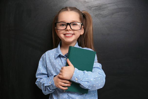 Cute little child wearing glasses near chalkboard. First time at school - Foto, Bild
