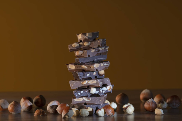 Pile de morceaux de chocolat entourés de noisettes
 - Photo, image