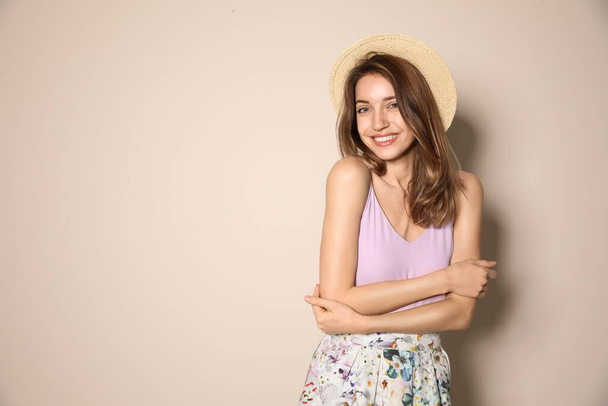 Young woman wearing floral print skirt and straw hat on beige background. Space for text - Foto, immagini