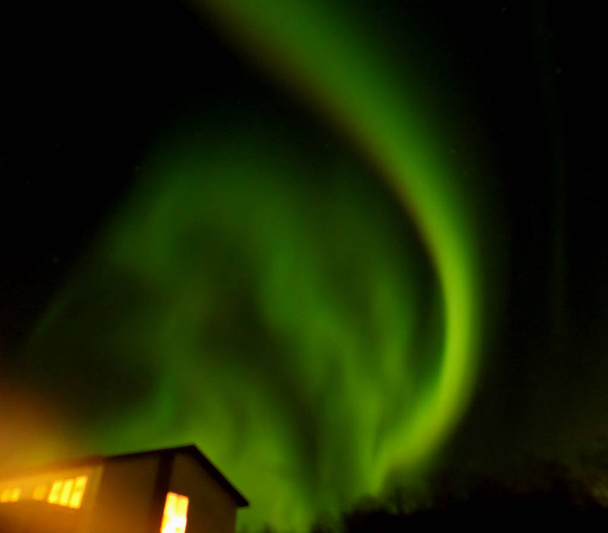 Neuvěřitelná aurora borealis jiskřící nad malým městečkem na severu Islandu - Fotografie, Obrázek
