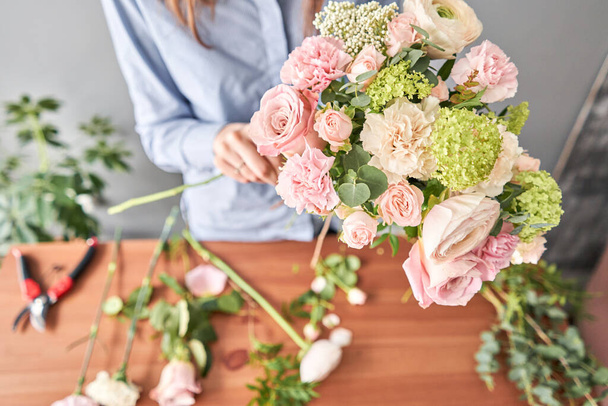 Woman florist creating beautiful bouquet in flower shop. Work in flower shop. Flowers delivery. - Foto, afbeelding