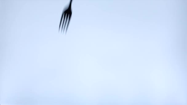 silueta kovové vidlice a lžíce padající na stůl na bílém pozadí - Záběry, video