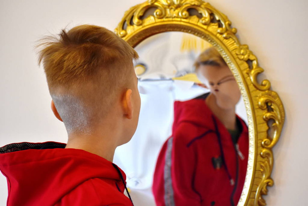 The child reflected in a distorting mirror. A fun reflection of the boy. Children's entertainment - Foto, imagen