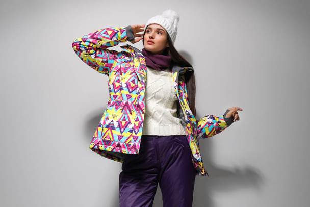 Женщина в стильной зимней спортивной одежде на светло-сером фоне
 - Фото, изображение