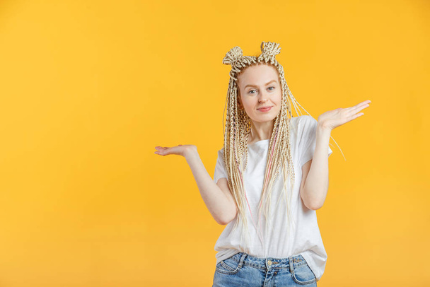 Jeune femme blonde caucasienne gestes et montre avec les mains des excuses pour les inconvénients. Portrait isolé sur jaune avec copespace. - Photo, image