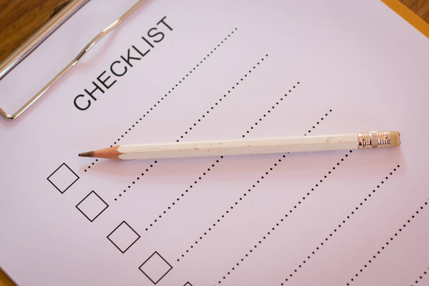 Conceito de lista de verificação - lista de verificação, papel e uma caneta com palavra de lista de verificação na mesa de madeira
 - Foto, Imagem