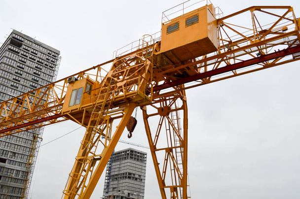 Високоякісний важко жовтий металевий несучий будівельний стаціонарний промисловий потужний козловий кран мостового типу на опорах для підйому вантажів на сучасному будівельному майданчику будівель і будинків
 - Фото, зображення