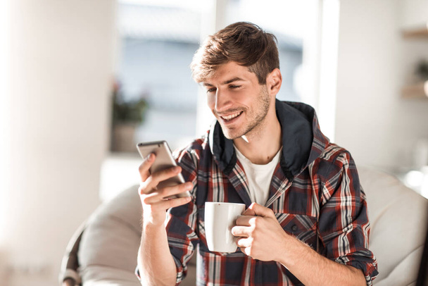 attractive young man drinking coffee and reading SMS. - Foto, Imagem