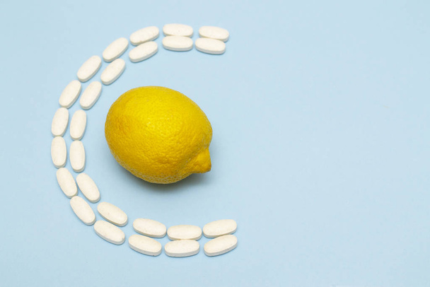 Βιταμίνη C χάπια με λεμόνι σε μπλε φόντο με αντίγραφο χώρου. - Φωτογραφία, εικόνα