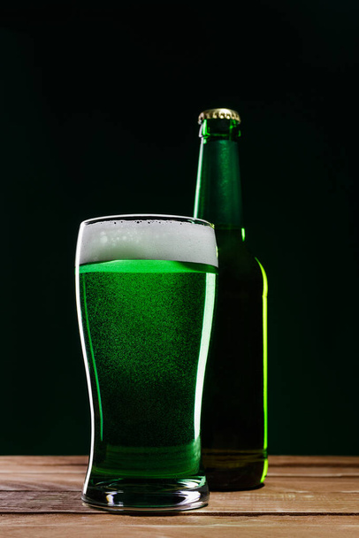 Glass of green beer and bottle on wooden table. St. Patrick's Day concept. - Photo, Image