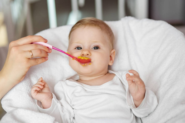 Mamá alimenta al bebé con puré de verduras. El concepto de la infancia, el cuidado, el primer señuelo y la comida para bebés
. - Foto, Imagen