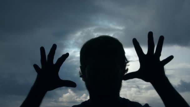 Silhouet van een griezelige man met trillende handen en vingers komt op camera aanvallen met overgang naar zwart. - Video