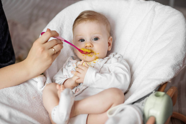 Mamá alimenta el puré de verduras infantil. El concepto de la infancia, el cuidado, el primer señuelo y la comida para bebés
. - Foto, imagen