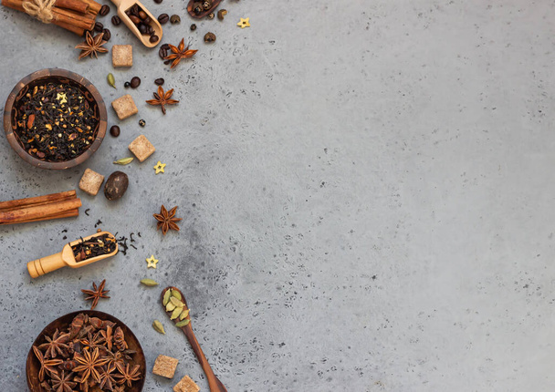 Ingredients for making spicy Indian masala chai tea or coffee. Dried black tea, roasted coffee beans, dry anise star seeds, cinnamon sticks, cardamom, black pepper and brown sugar. - 写真・画像