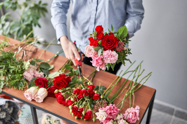 Kobieta kwiaciarnia tworząc piękny bukiet w kwiaciarni. Praca w kwiaciarni. Dostawa kwiatów. - Zdjęcie, obraz