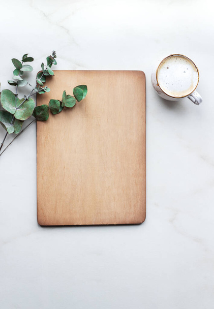 Office desk with Clipboard wood mockup , coffe cup and eucalyptus leaves. - Photo, image
