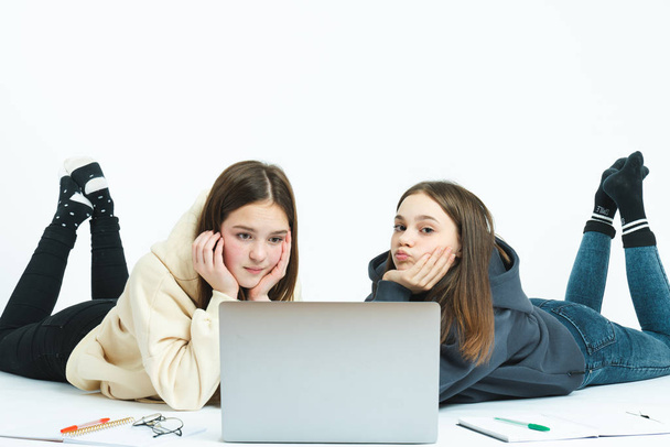 Upset girls school friends liying on the ground with laptop, dont no how to solve homework, isolated over white background - Foto, Bild