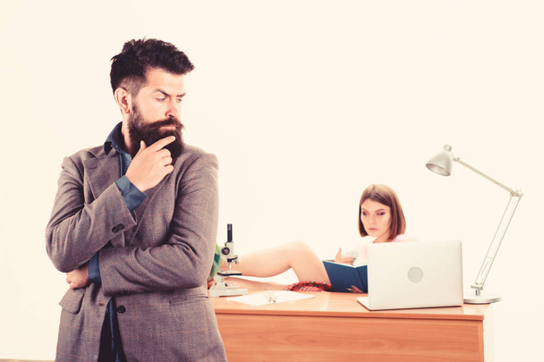 Looking like big boss man. Bearded man looking at sexy woman working in background. Confident business man and secretary in office. Brutal caucasian man with long beard in business wear - Photo, image