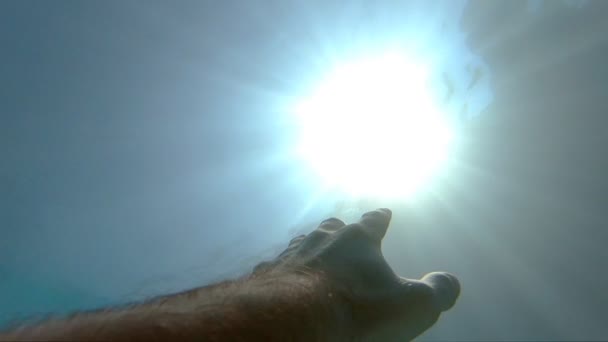 Arm asking for help and trying to reach to the sun. Point of view of man drowning in the sea or ocean and floating to the surface. Male hand stretches from under the water to sunrays. Slow motion POV - Footage, Video