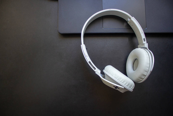 Бездротові навушники, що лежать на ноутбуці на офісному столі
 - Фото, зображення