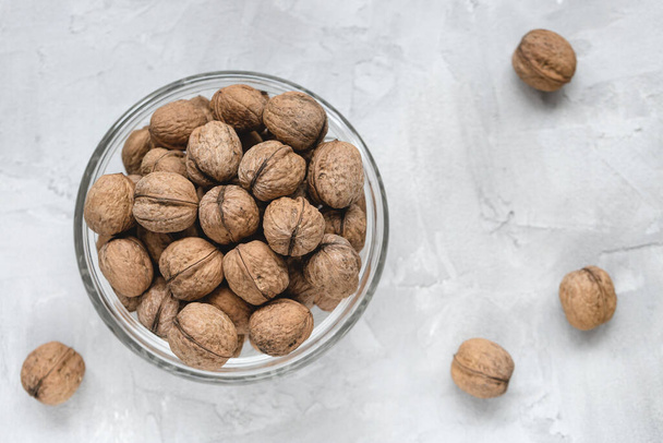 Walnuts in shell in bowl on gray background - Photo, Image