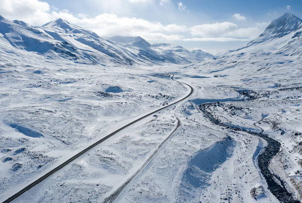 Aerial view of a winding road among the snowy mountains in the north of Iceland - Foto, imagen