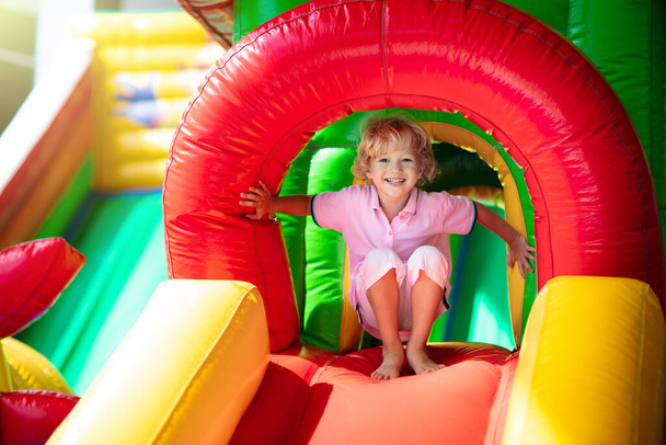 Criança pulando no trampolim playground colorido. As crianças saltam no castelo inflável do salto na atividade da festa de aniversário do jardim de infância e no centro do jogo para a criança pequena. Menino brincando ao ar livre no verão. - Foto, Imagem