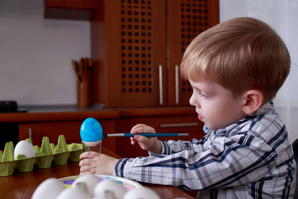 Little boy paints eggs with colored paints - Foto, imagen