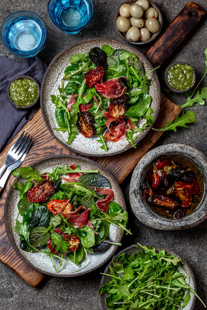 Salad with arugula, spinach, dried tomato and ham serrano paleta iberica. Low carbs keto recipe - Фото, изображение