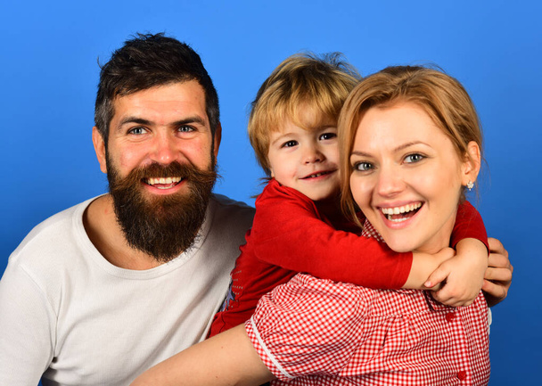 Mother, father and son with smiling faces hug on blue - Fotoğraf, Görsel
