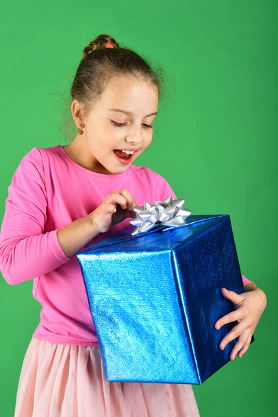 Child with curious smiling face poses with present - Foto, Imagen