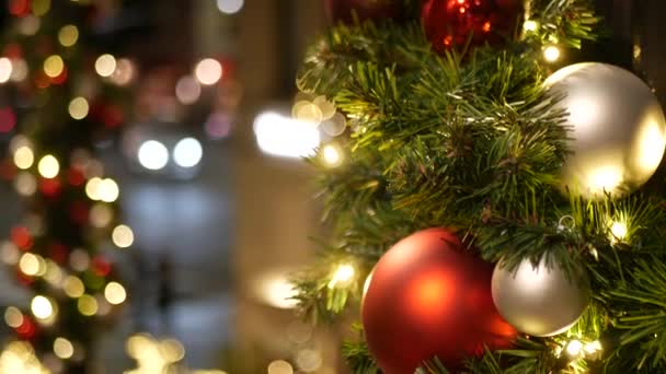 Primo piano di albero di Natale all'aperto festosamente decorato con palline rosso vivo su sfondo fata frizzante sfocato. Luci a ghirlanda sfocate, effetto Bokeh. Strada notturna sfocata con auto su strada
 - Filmati, video