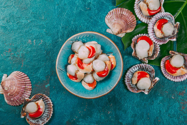 Raw fresh seafood shellfish scallops on blue background. - 写真・画像