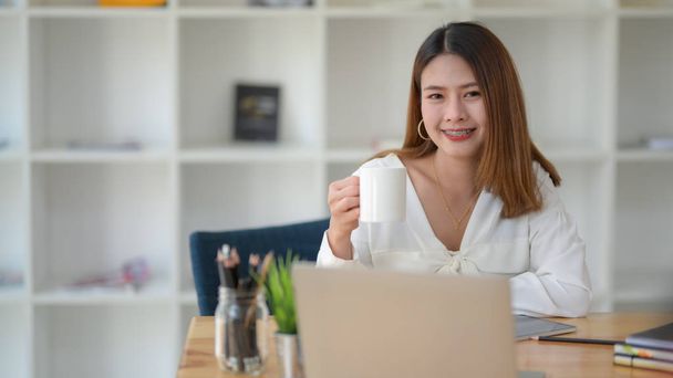 Vista de perto de mulheres de negócios felizes fazer uma pausa e beber café enquanto trabalhava no local de trabalho moderno
 - Foto, Imagem