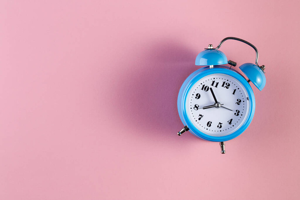 Blue vintage alarm clock on light pink color background. Alarm clock with place for text. Time management concept, business planning - Fotoğraf, Görsel