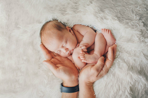 Egy újszülött, aki a szülők kezén fekszik. Baba utánzása a méhben. Gyönyörű kislány, aki a hátán alszik. a szeretet megnyilvánulása. Egészségügyi koncepció, szülőség, gyermeknap, orvostudomány, Ivf - Fotó, kép