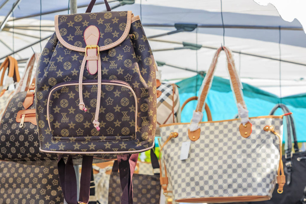 Fake high-end fashion brand name famous designer purses and backpacks on display for sale at a local outdoor flea market in Ventimiglia, Italy - Photo, Image