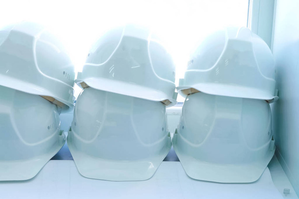 Bílé helmy dělníků leží na parapetu. Ochranná přilba. - Fotografie, Obrázek