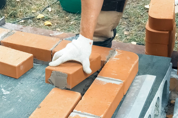 Egy férfi téglafalat épít. Brick feltette az oldatot. Téglaház építése. - Fotó, kép