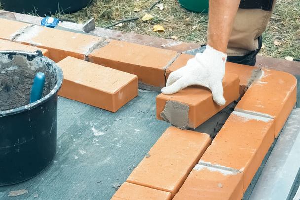 Un homme construit un mur de briques. Brick a mis la solution. Construction d'une maison en brique
. - Photo, image