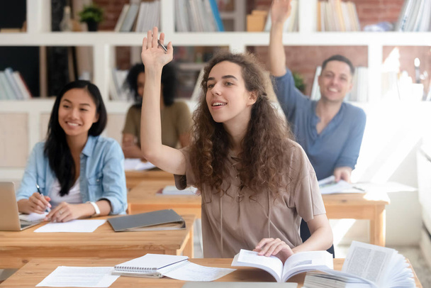 Sorridente adolescente ragazza studente alzando la mano, ponendo domanda a lezione
 - Foto, immagini
