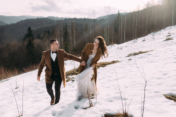 le marié avec la mariée pour une promenade dans la forêt sur fond de neige blanche
. - Photo, image