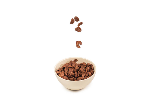 Chocolate corn flakes falling to the white bowl isolated on white. Motion. Copyspace. - Fotó, kép