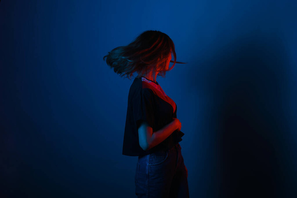 Young girl shaking with her hair on blue background lighted with - Φωτογραφία, εικόνα