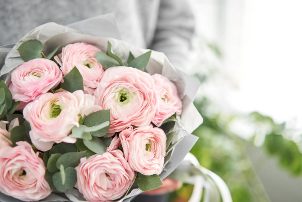 Bunch pale pink ranunculus flowers with green eucalyptus. The work of the florist at a flower shop. - Zdjęcie, obraz