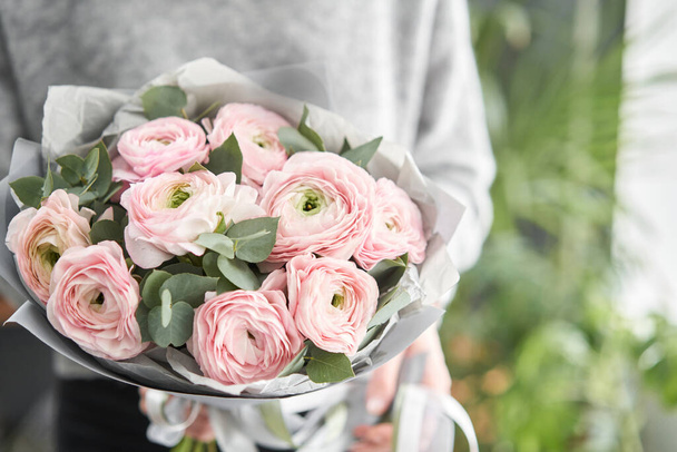 Ramo de flores de ranúnculo rosa pálido con eucalipto verde. El trabajo de la floristería en una floristería. - Foto, Imagen