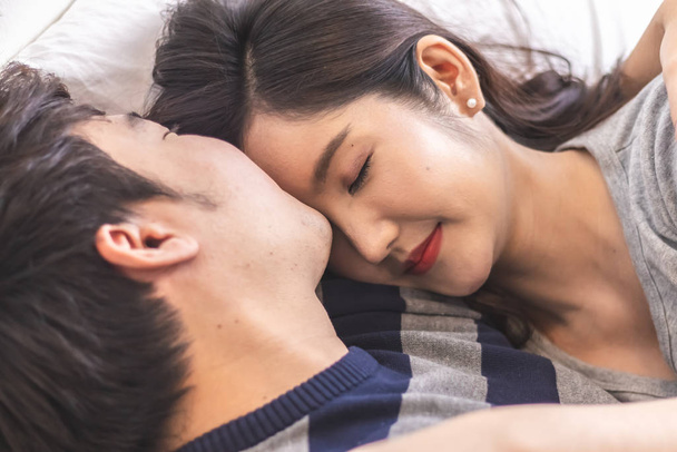 Lovely attractive young Asian couple man kiss forehead of happy woman with and hug in romantic moment. Warm heart marriage and lover bonding and relationship. Husband and wife in love photo concept. - Fotoğraf, Görsel
