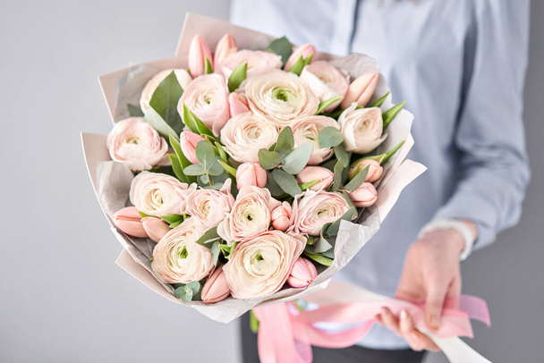 Mazzo di tulipani rosa pallido e fiori ranuncoli con eucalipto verde. Il lavoro del fioraio in un negozio di fiori
. - Foto, immagini