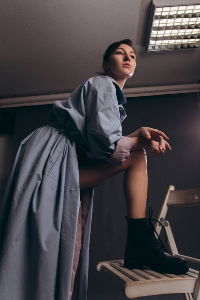 A girl in a blue trench coat is in an aggressive pose. Photo taken in studio.  - Fotó, kép